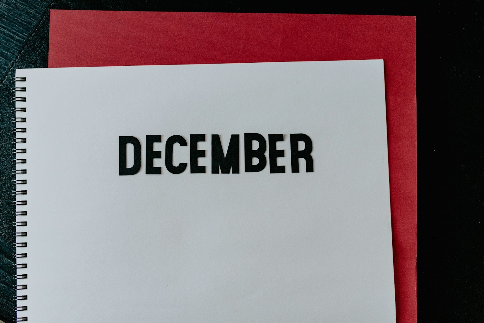 A minimal desk calendar open to a single date page, softly lit against a muted gray background, edges slightly out of focus.