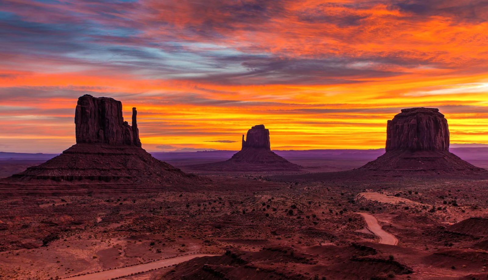 Silhouette of layered desert hills receding into the distance at golden hour, warm amber light defining each ridge against a glowing sky