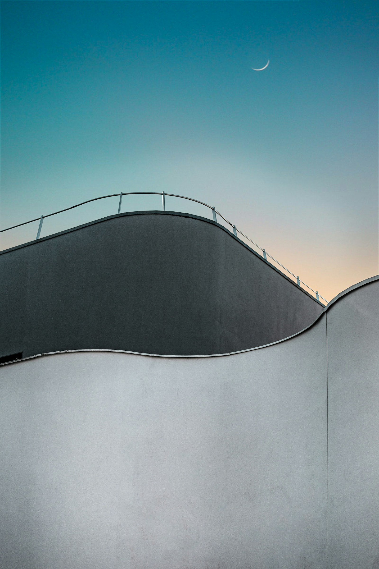 Low-angle view of a grey concrete architectural structure against an overcast sky, clean geometric lines and raw surface texture visible