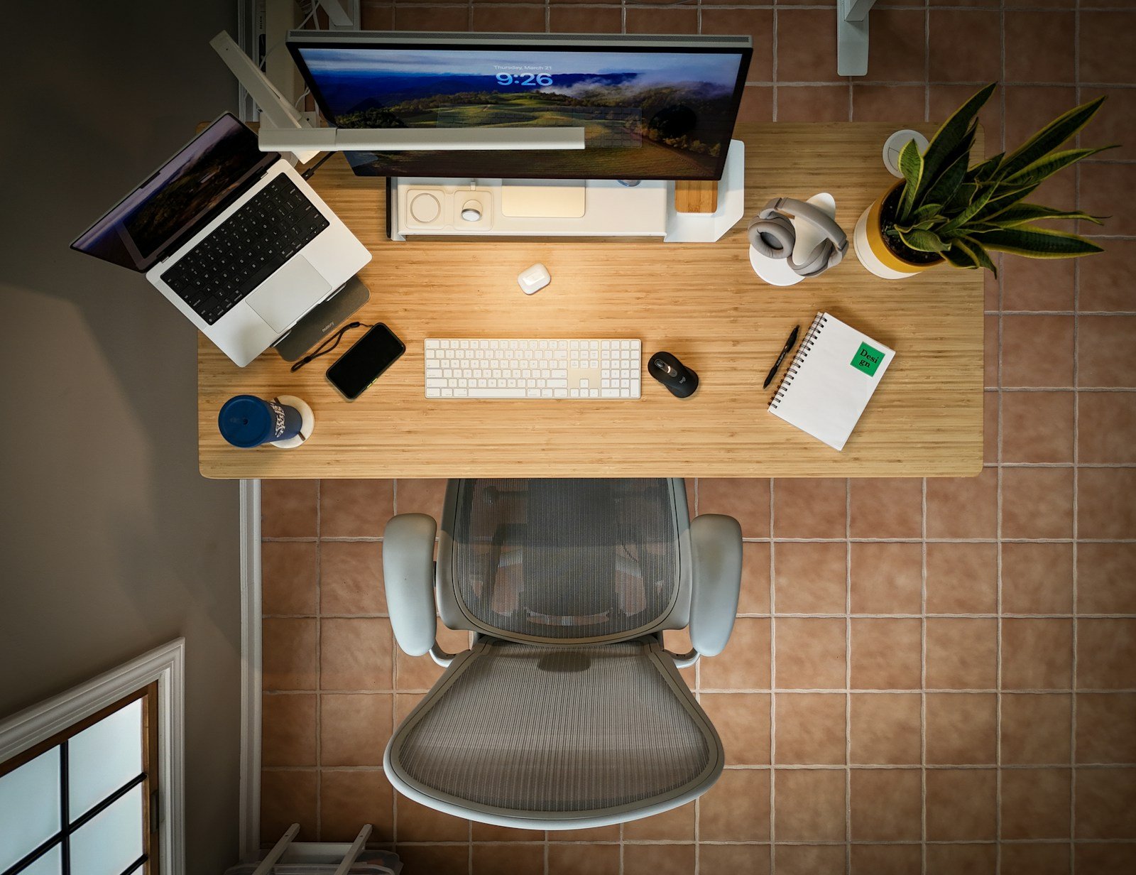 An overhead view of a desk with a laptop, keyboard, and mouse under artificial light, the clinical aerial perspective of a workspace under audit, mechanical and technical in its arrangement
