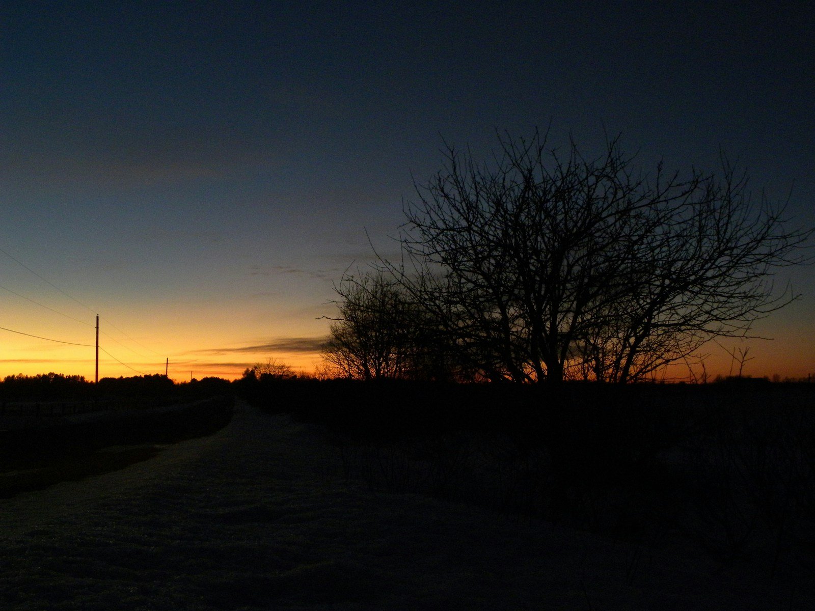 A dawn landscape with warm amber light breaking over a single path leading toward a distant horizon, the sky split between fading darkness and emerging light.