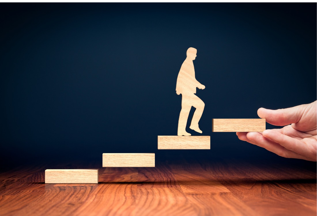 Hand supporting professional climbing leadership development steps representing tailored coaching.