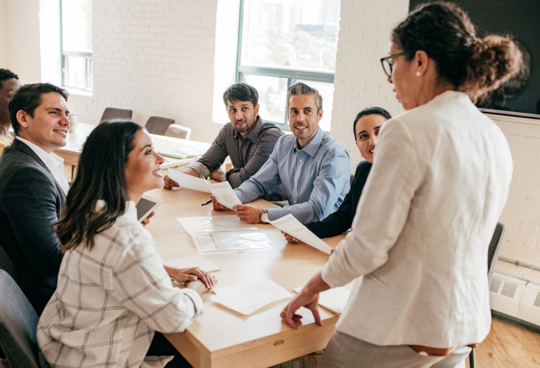 Female leader presenting to diverse business team in a meeting room.