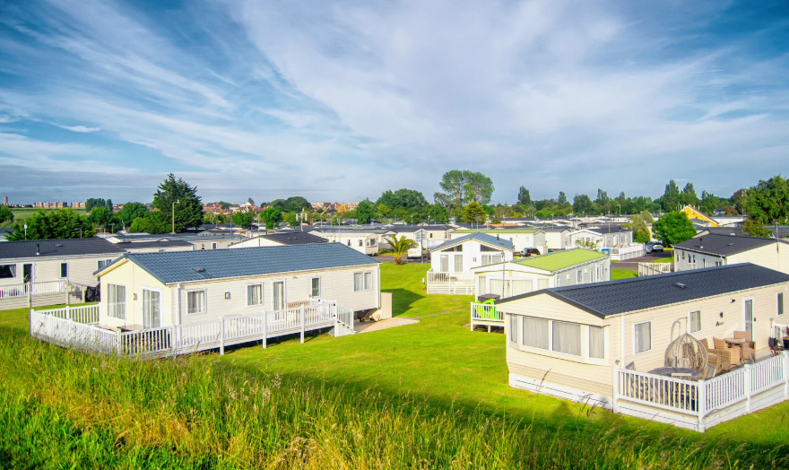 A group of static caravans set up on grass with showers cubicles inside them.