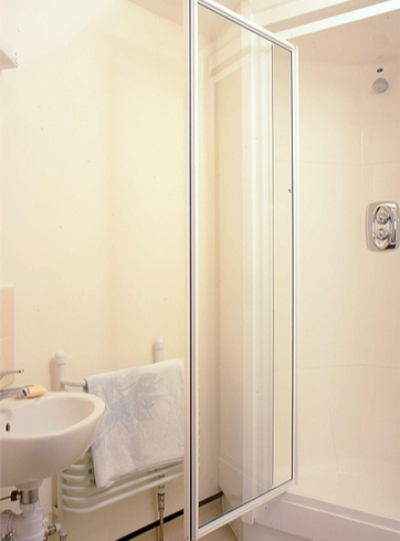 A freestanding shower cubicle being used in a bathroom with limited space.
