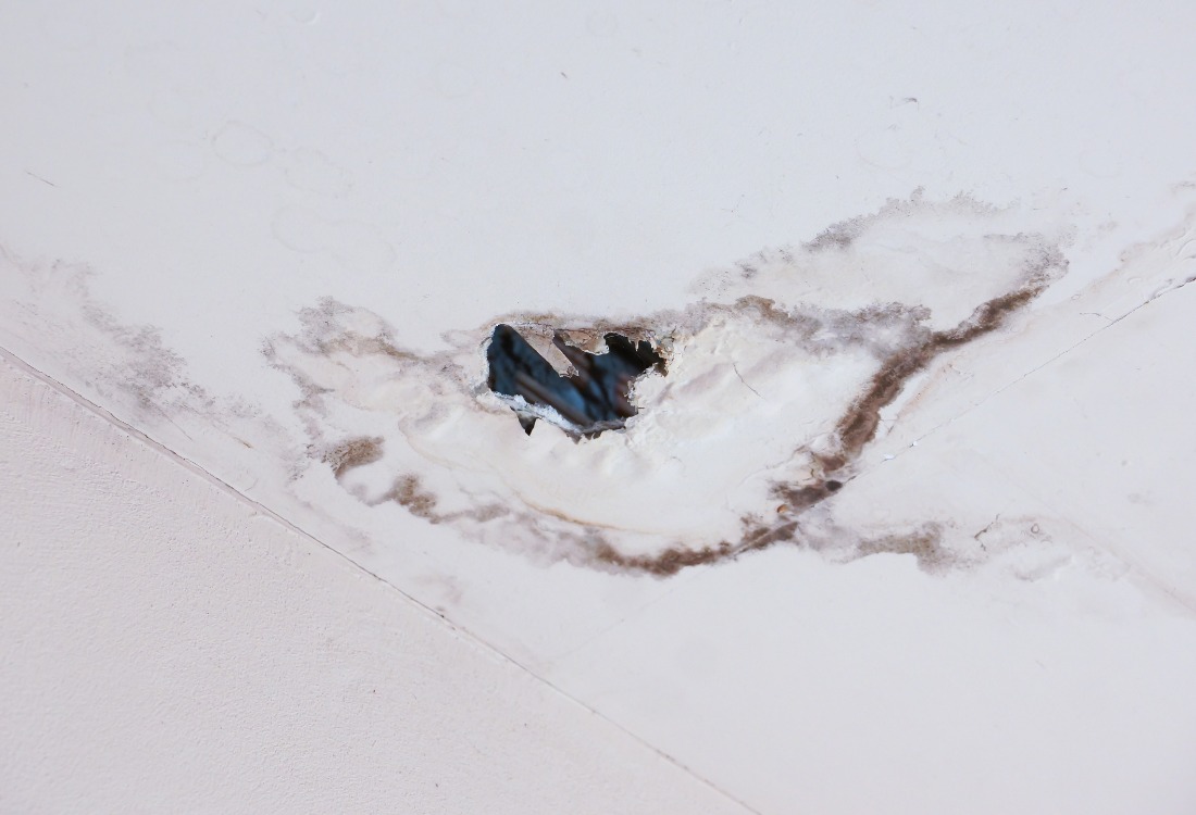 A ceiling with a hole caused by a leaking shower above.