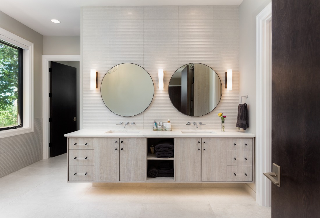 A luxury bathroom with two mirrors, a bathroom cabinet and lights.