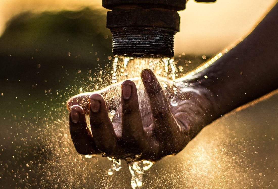 Water flowing from a pipe into a person’s hand, symbolising water conservation and reuse.