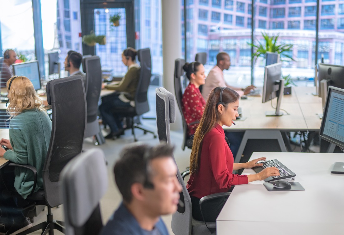 Employees in an office using a job ticketing system whilst on calls with customers. 