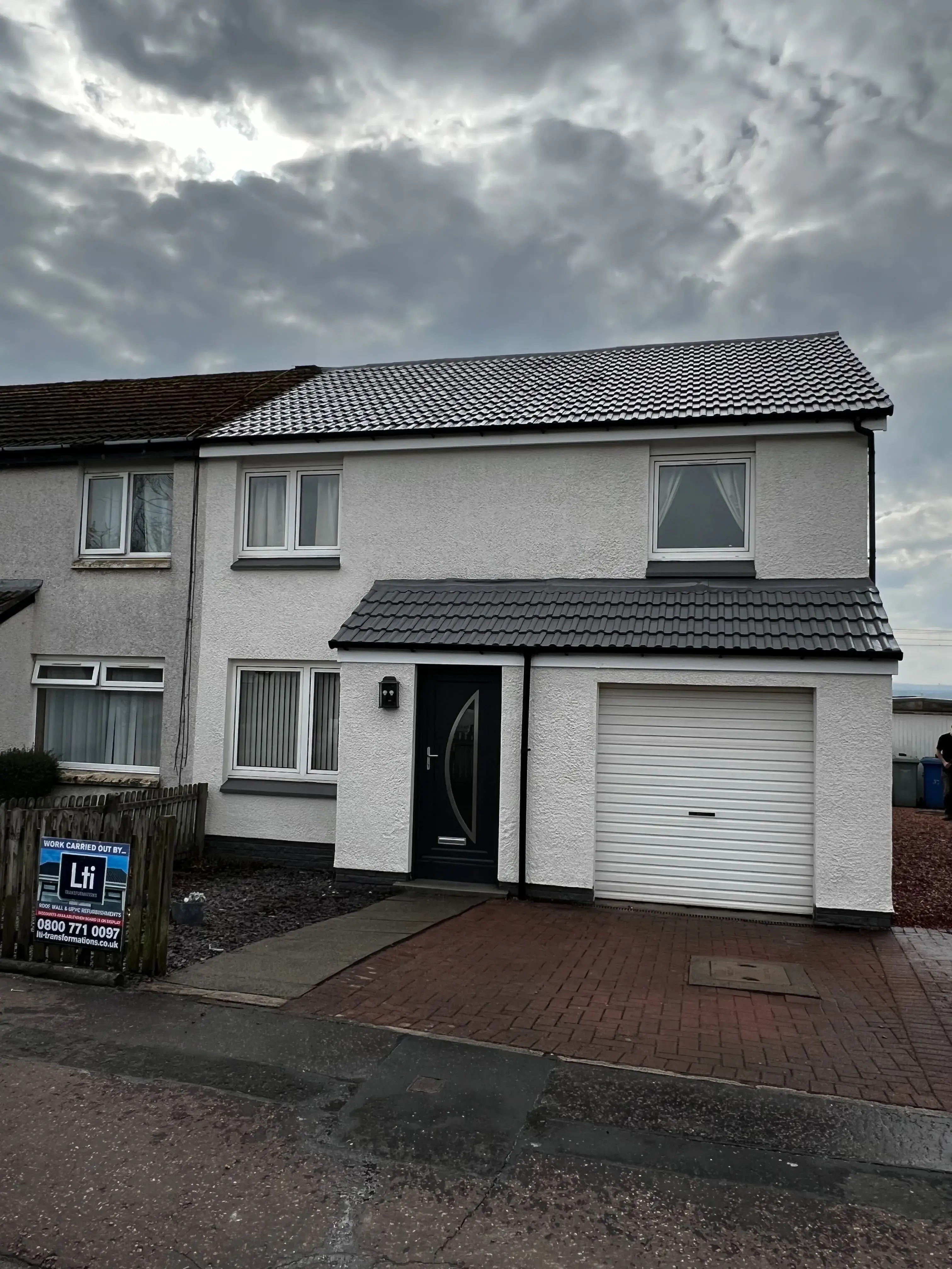 Front view of a two-storey Scottish home with a newly coated roof under a cloudy sky.
