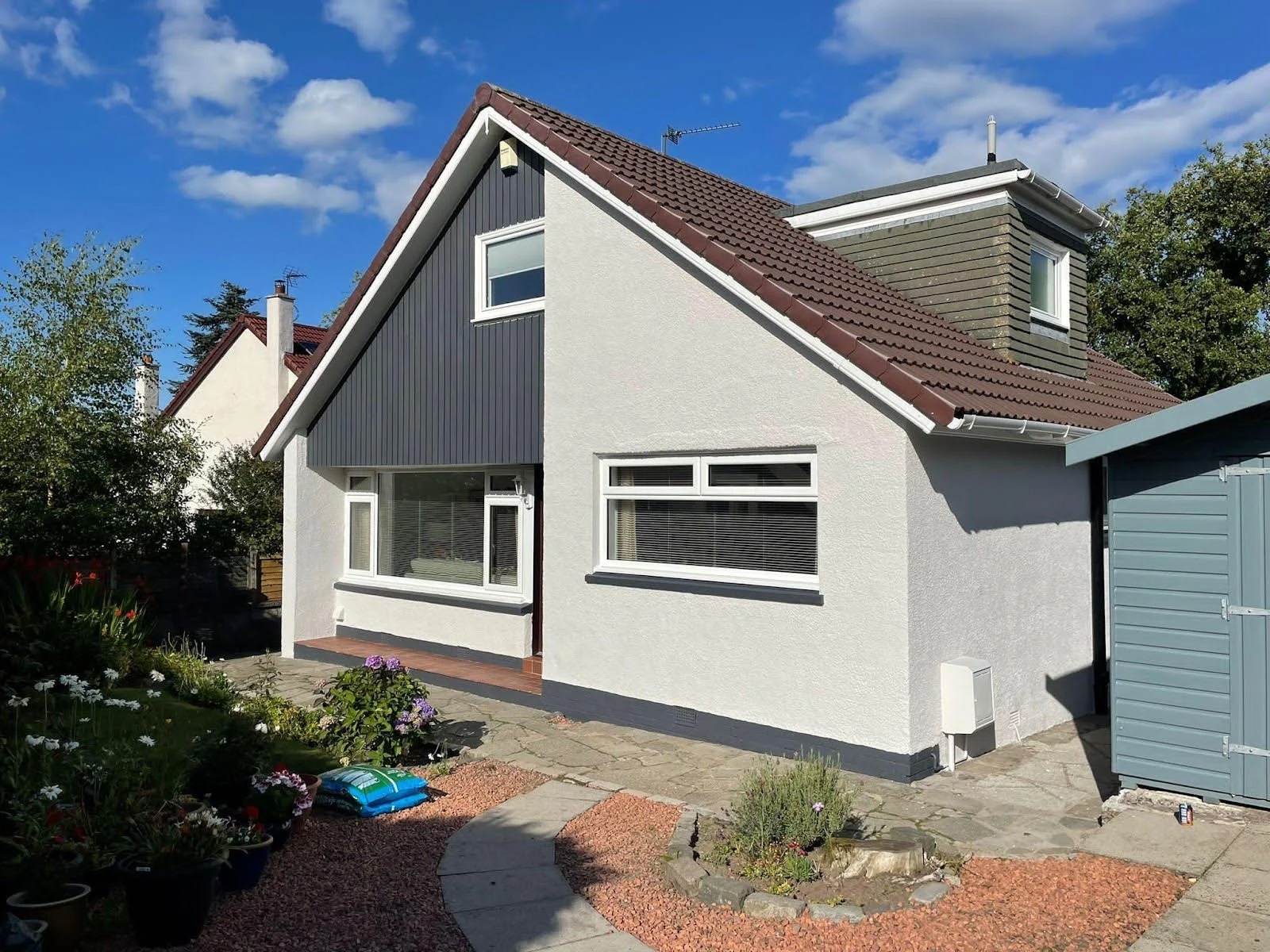 Front view of a Scottish home with a clean, freshly coated roof on a bright sunny day.