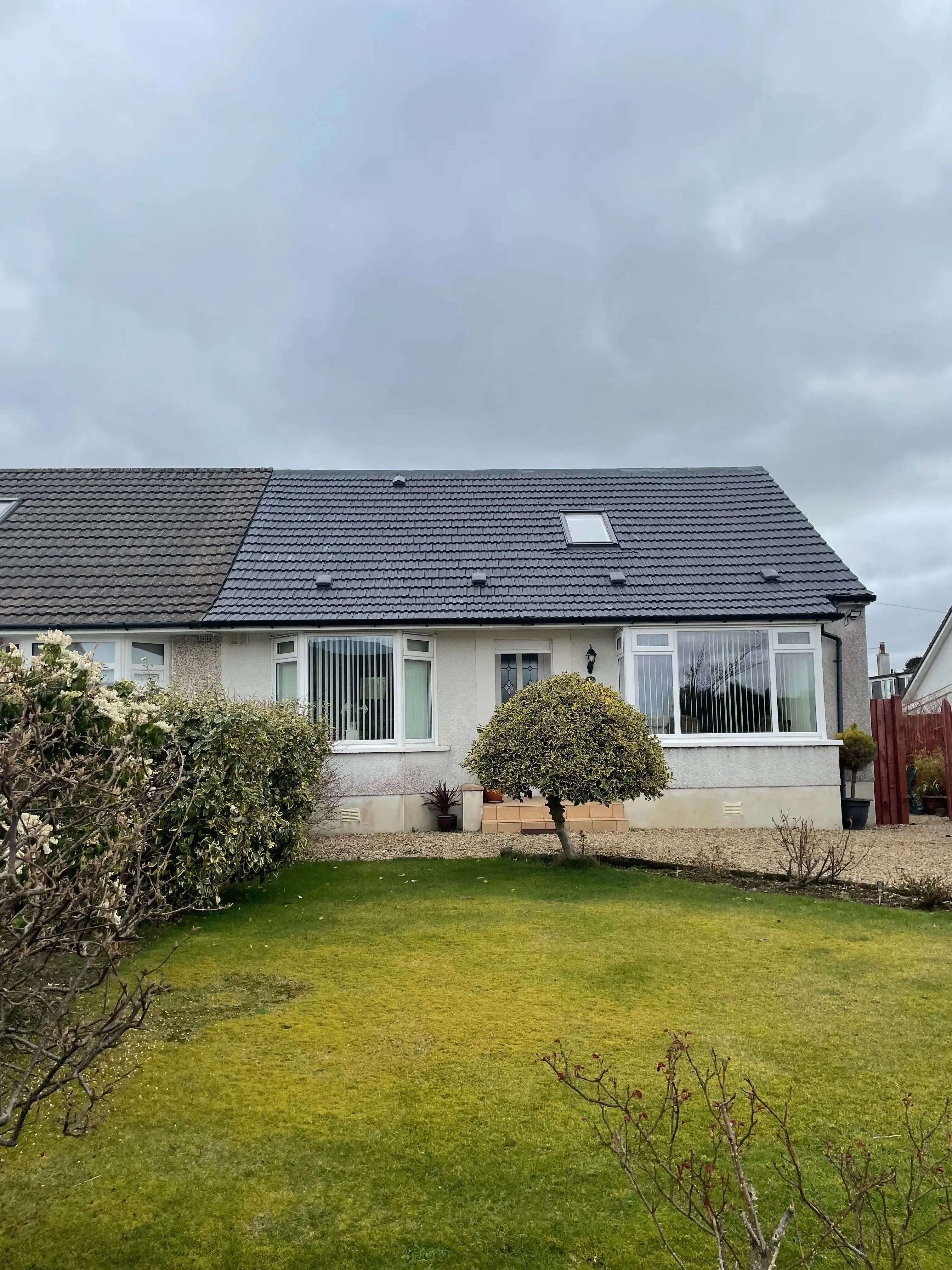 Single-storey Scottish home with a clean, freshly coated roof and a front lawn under an overcast sky.