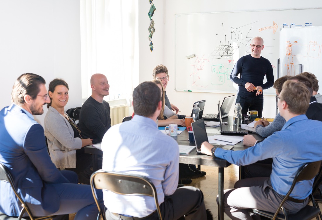 A diverse group of professionals collaborating in a modern meeting room, representing a company working to foster a positive organisational culture within a complex structure.