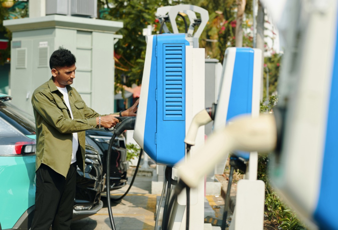 Driver charging an electric vehicle at a public EV charging station.