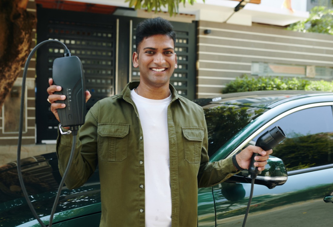 EV owner holding a charger as part of routine electric vehicle maintenance.