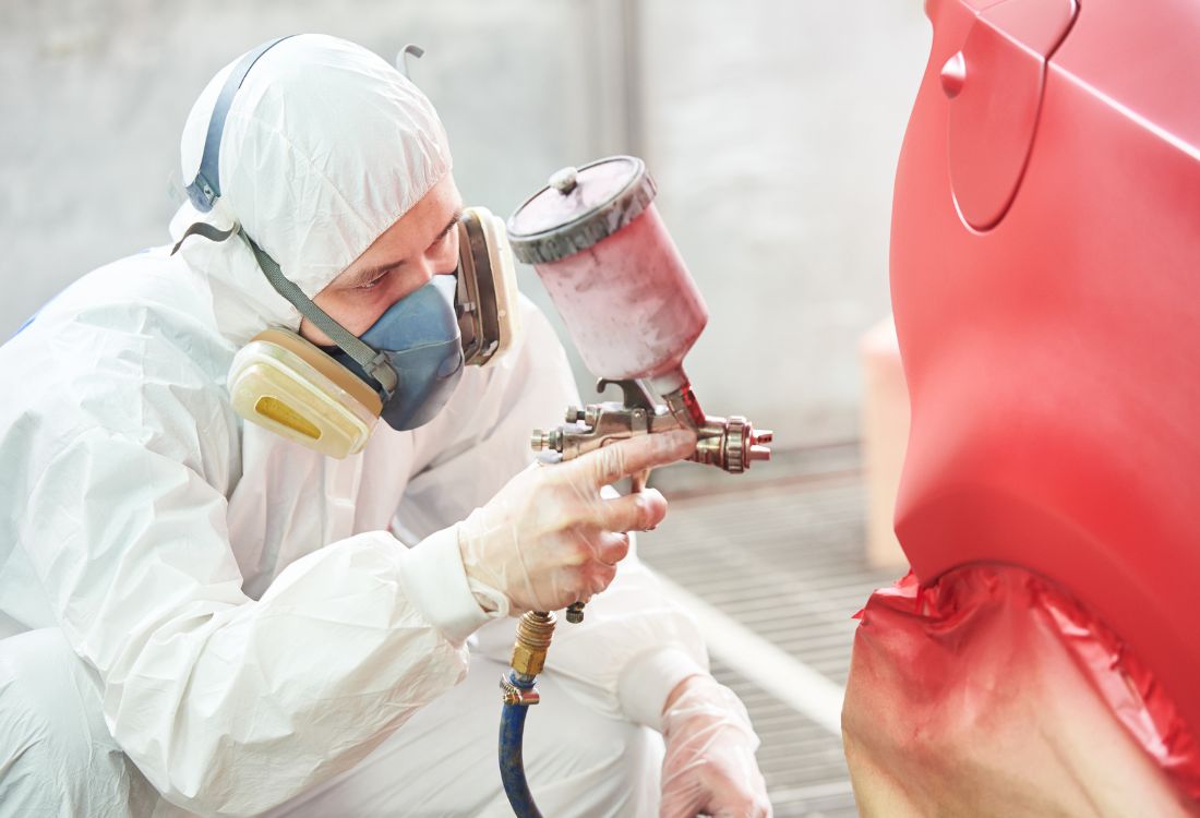 Technician in protective gear carrying out BMW-approved paintwork repairs to maintain insurance cover and long-term vehicle value.