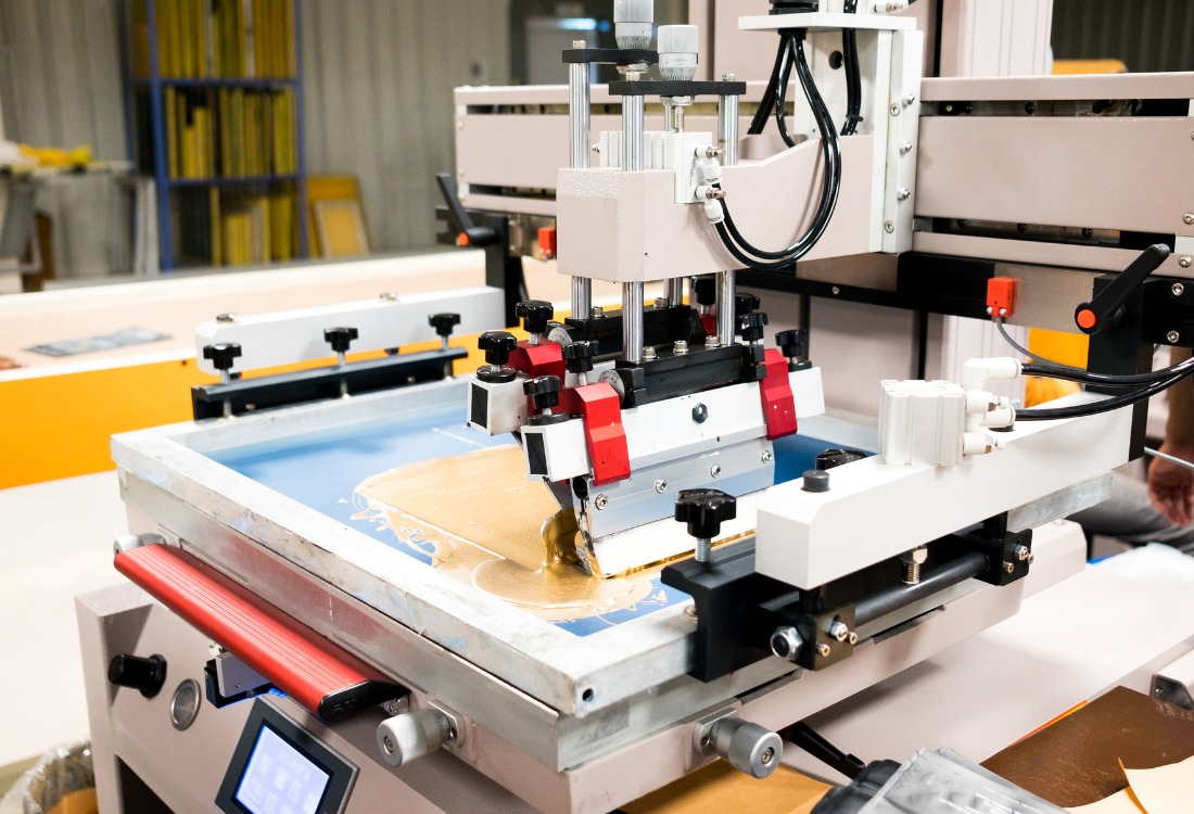 Screen and digital printing machine producing custom-printed pouches inside a packaging facility.