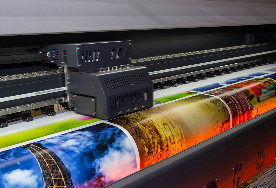 Large format printing machine printing a full-color poster.