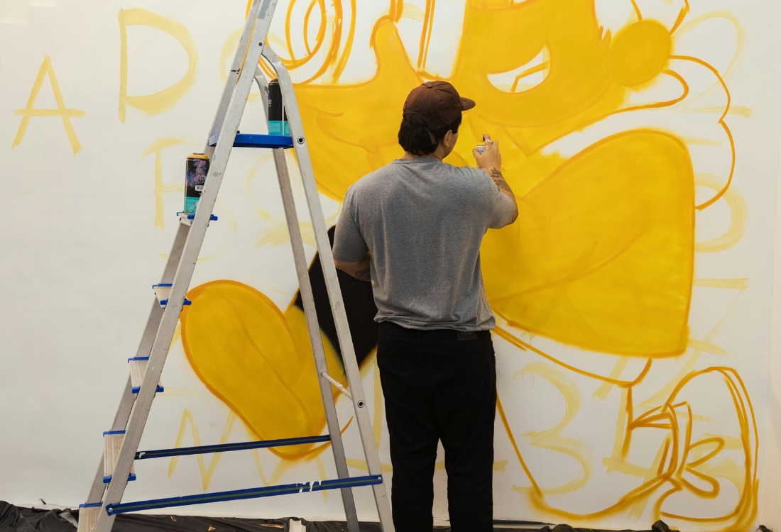 Artist creating custom printed wall covering with yellow geometric design for business branding.