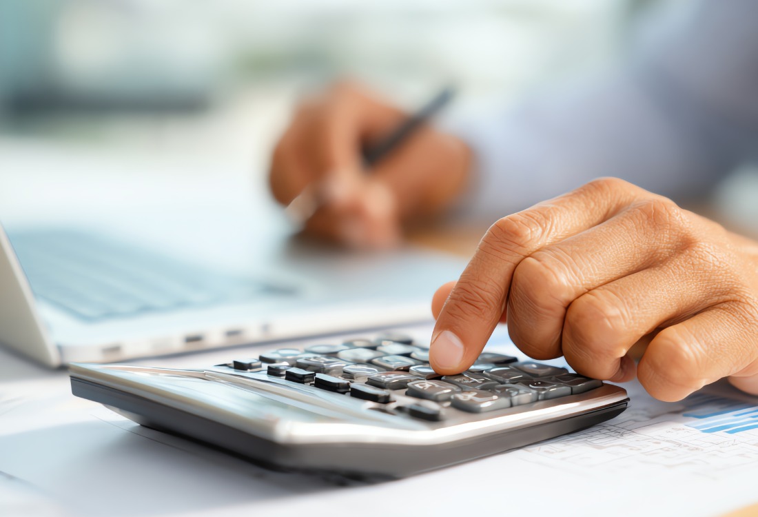 Business professional using calculator for financial planning and bookkeeping with documents.
