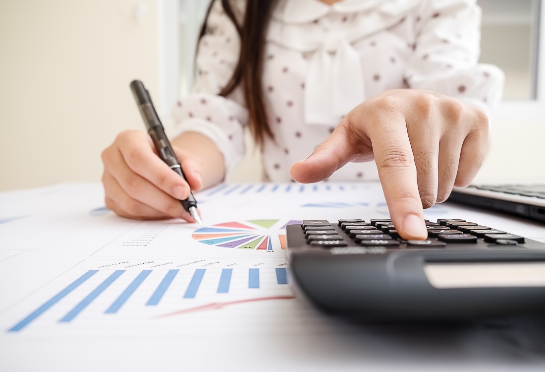 Business accountant analysing financial data at a desk with documents and a calculator. 