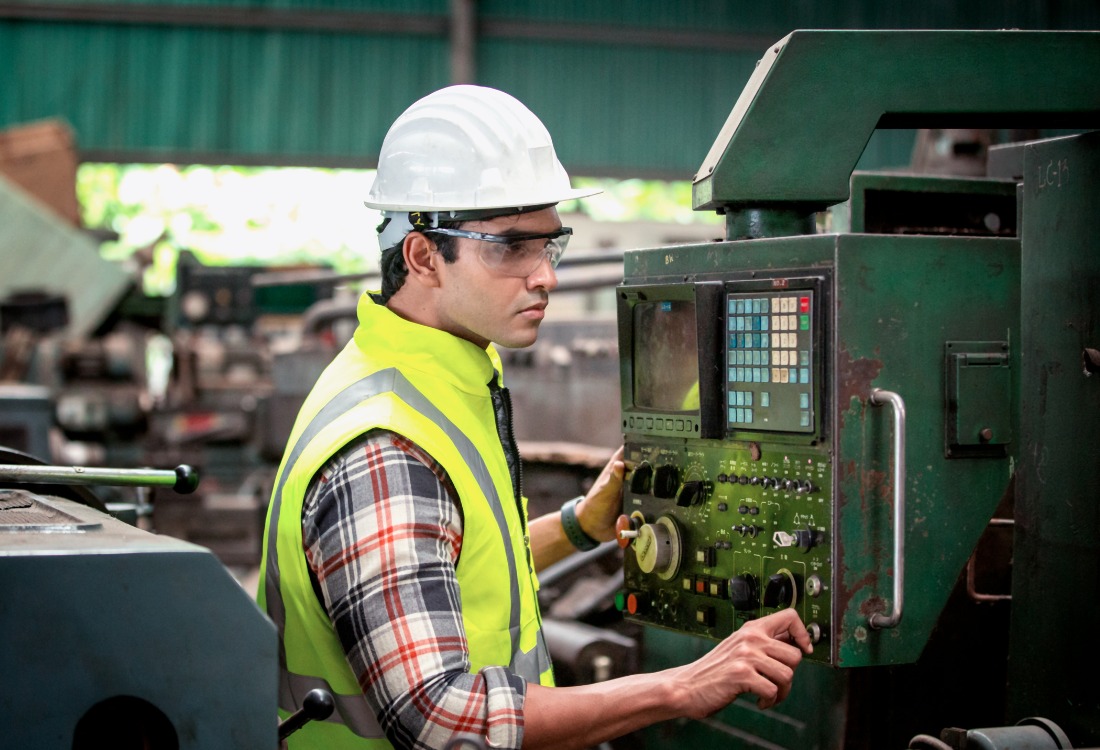 Factory worker operating operator friendly machinery in manufacturing industry. 