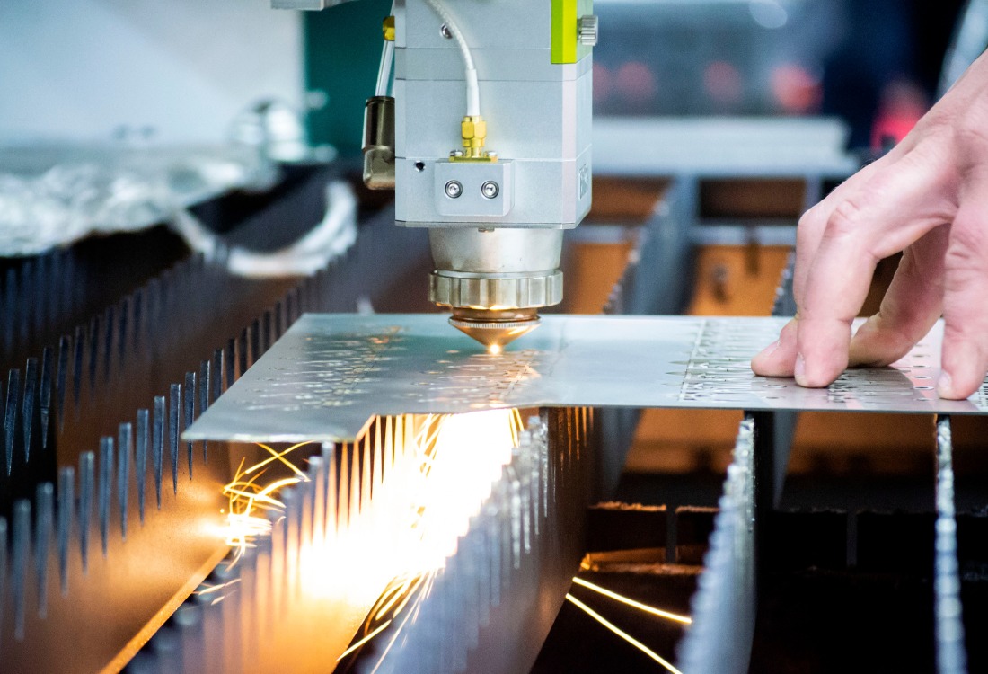 Laser cutting machine processing sheet metal with sparks flying during fabrication. 