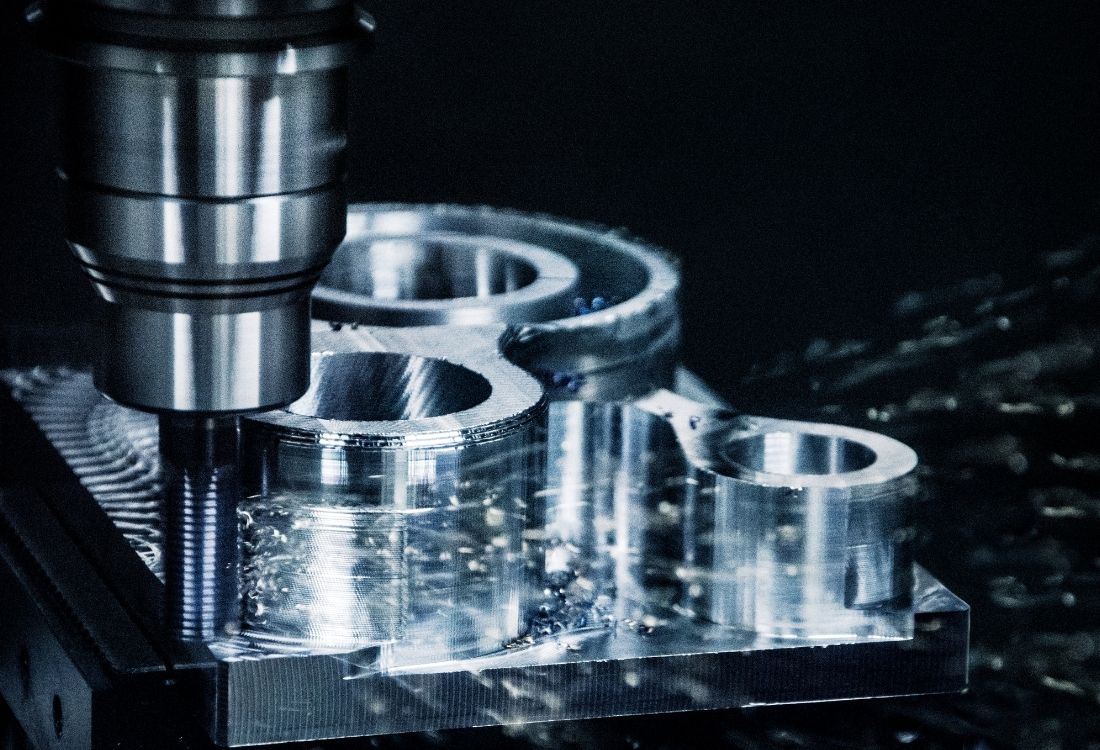Close-up of a computer-controlled milling machine cutting a metal part, highlighting the role of smart diagnostics and modern manufacturing technology in reducing downtime. 