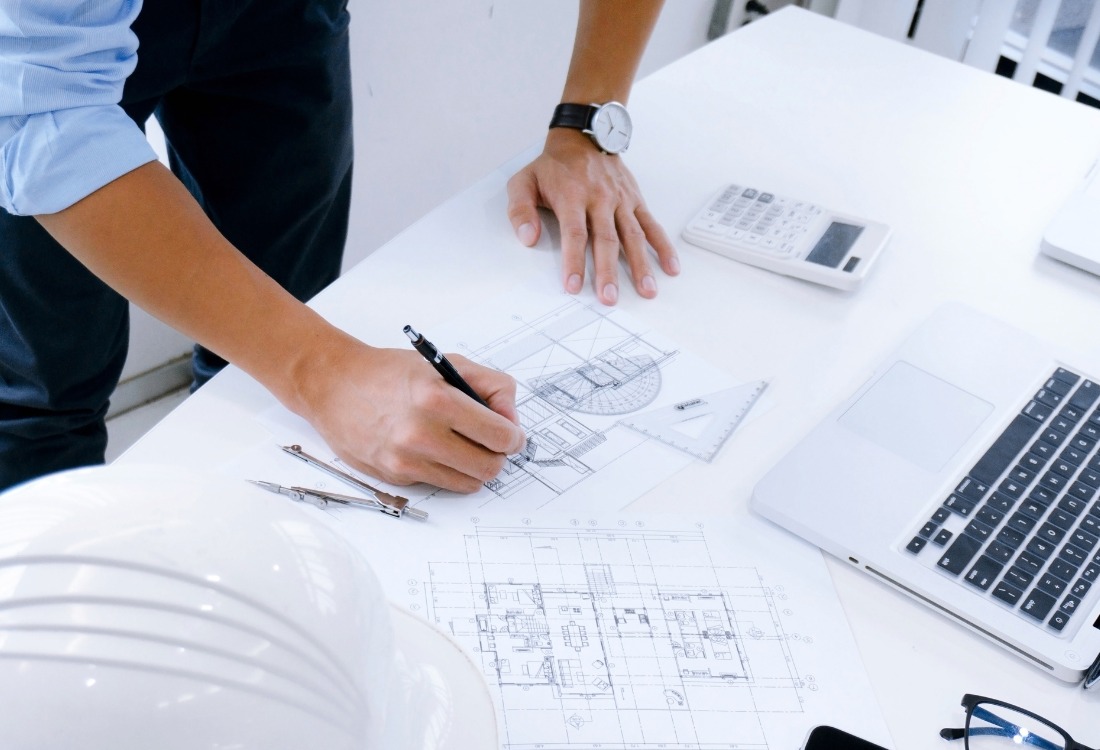 An architectural designer working a clients project after explaining what influences the cost of his services.