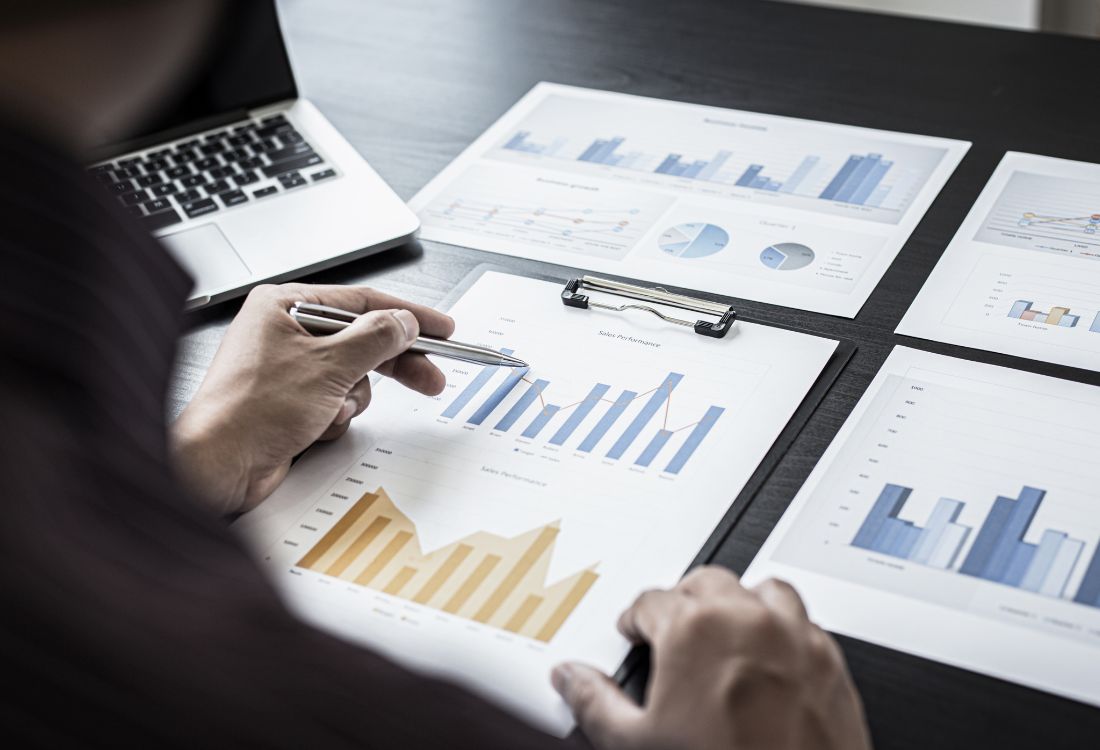 Person reviewing business charts and performance reports on a desk.
