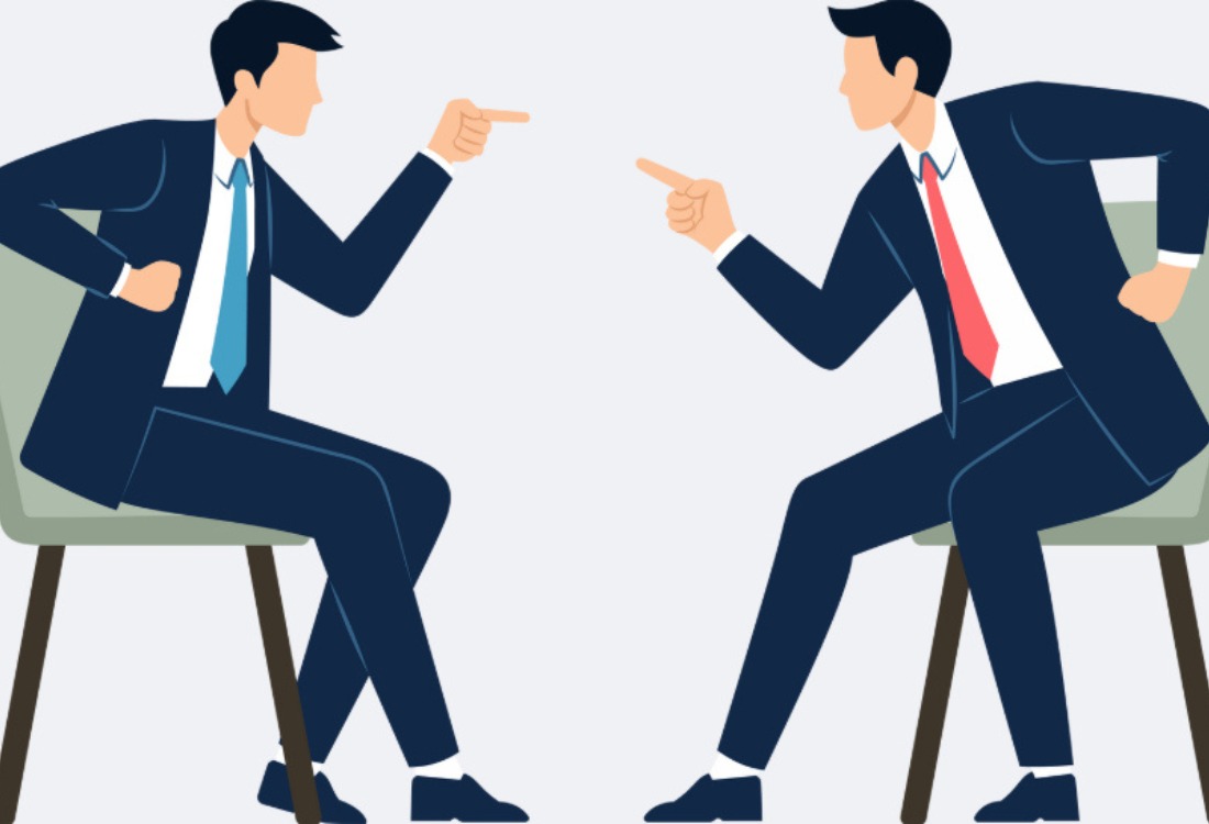 Two business professionals in a tense face-to-face discussion, symbolising conflicting leadership styles and the challenges of aligning management approaches after a merger.