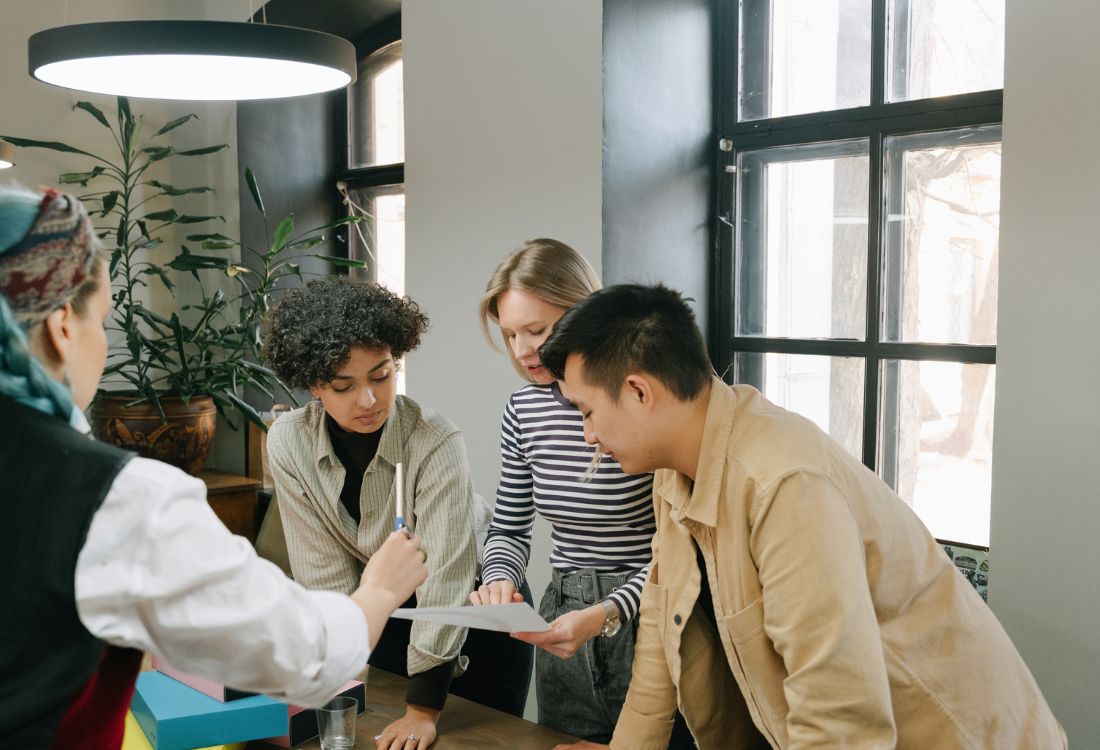 Colleagues collaborating around a table during a team discussion in a modern office.
