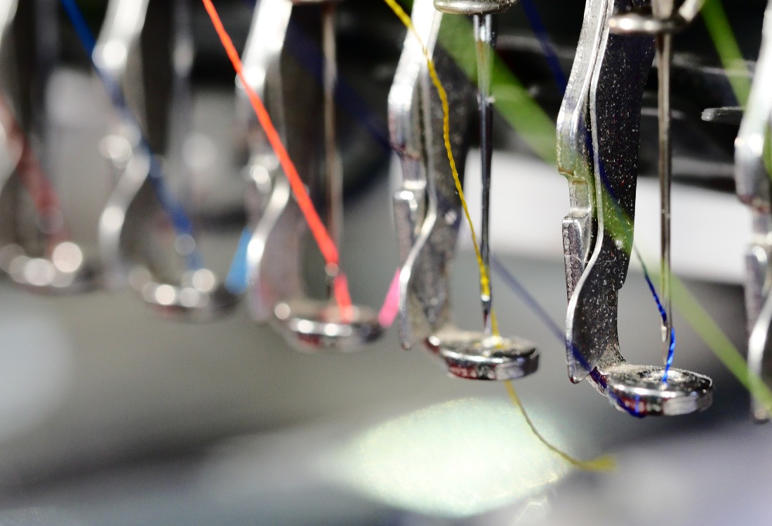 A close-up shot of an embroidery machine with the different coloured threads.