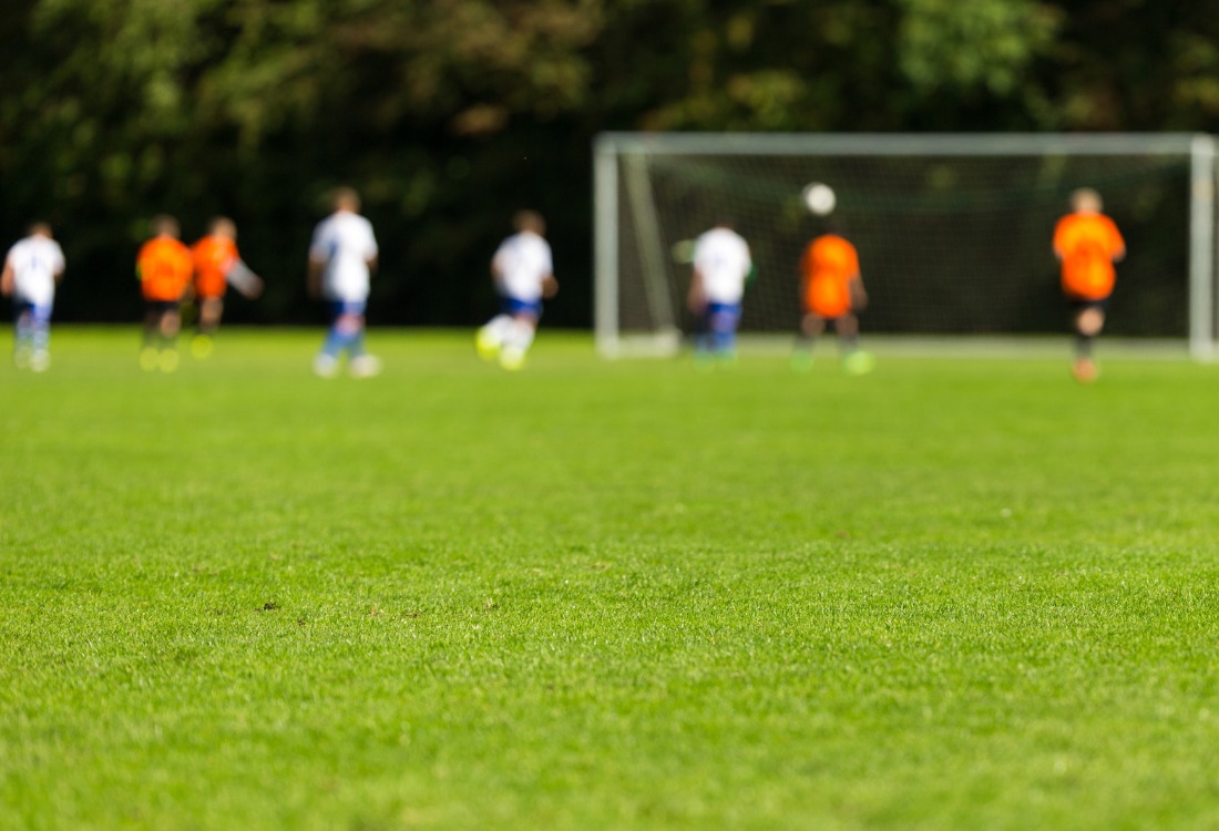 A youth football match taking place on a well-maintained grass pitch, representing the importance of strategic planning, investment, and local consultation in delivering effective playing pitch strategies.