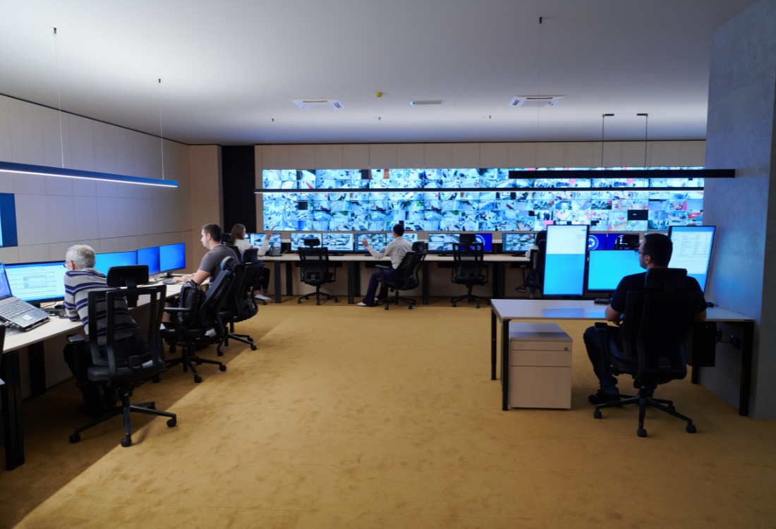 Office setup with multiple computer monitors displaying data and applications, highlighting key factors for business monitor selection.