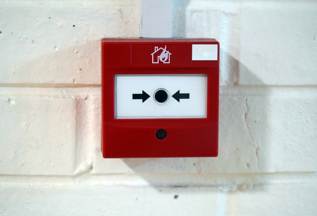 A fire alarm mounted on a wall that has been regularly tested and checked in an industrial building.