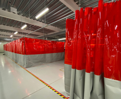 Blog cover image showing how to control temperature fluctuations in a warehouse with industrial partitions, featuring red and grey curtain walls that create distinct, climate-controlled zones.