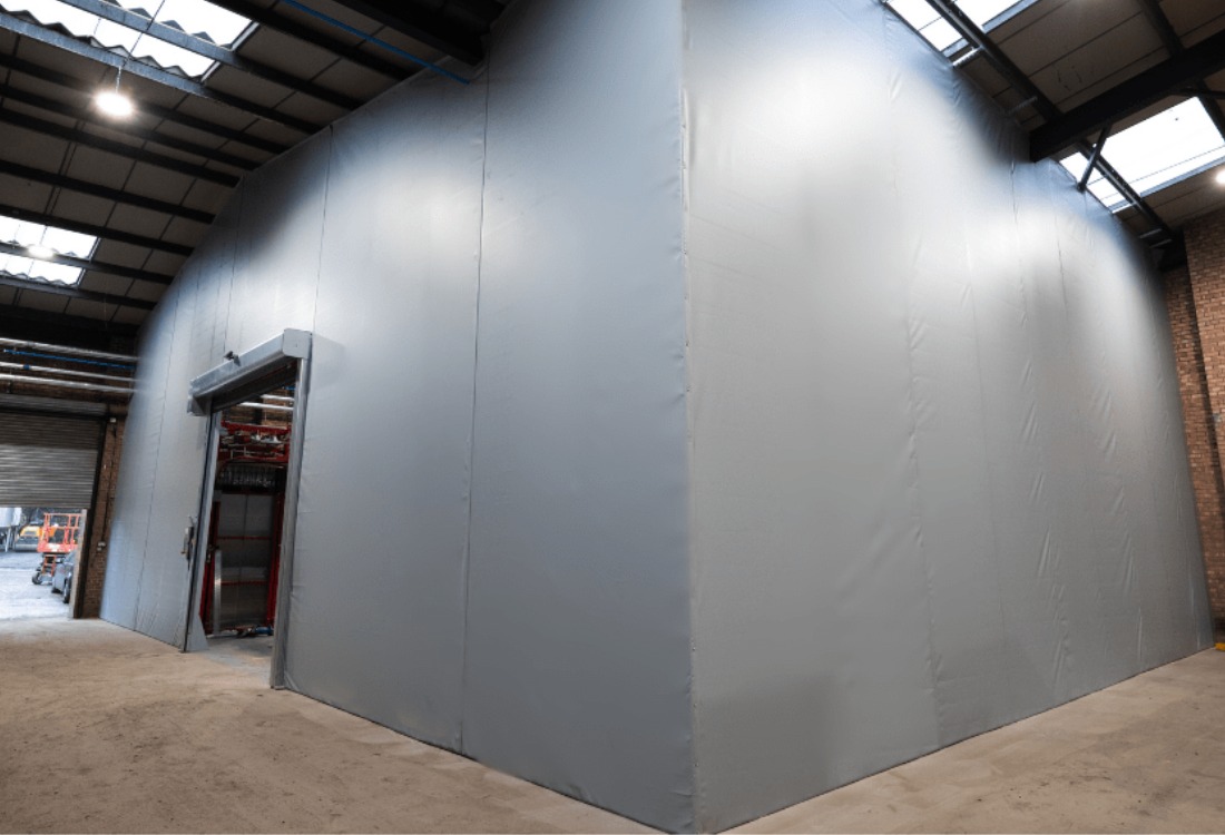 Industrial warehouse interior featuring grey steel partition walls with skylights above, demonstrating permanent steel partitioning solution for warehouse space division.