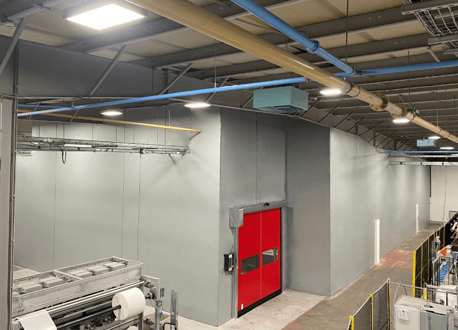 Grey partition walls with red high-speed door in industrial facility, showing enclosed warehouse partitioning system designed for climate control and dust containment