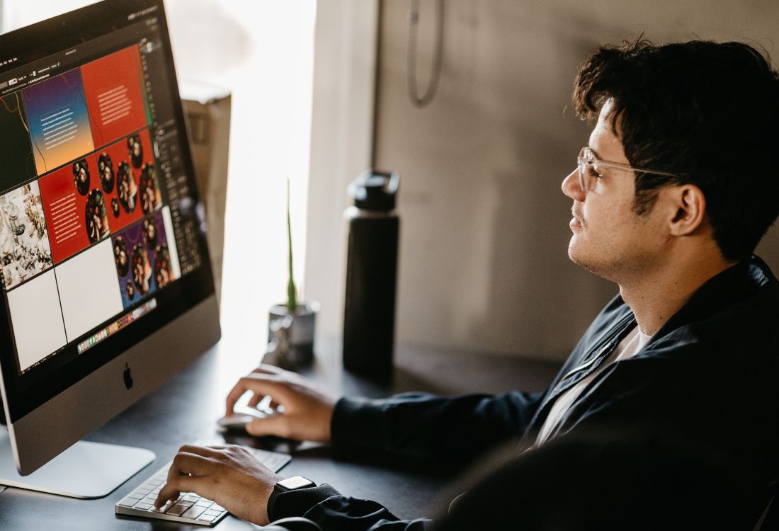 Person working at a desk on a computer displaying business-related graphics and documents.