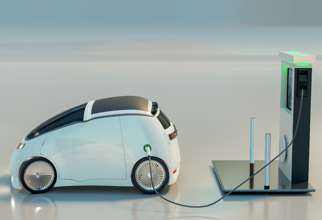 Modern electric vehicle connected to commercial EV charging station with green indicator light showing active charging, representing workplace charging infrastructure for UK businesses transitioning to electric fleet vehicles.