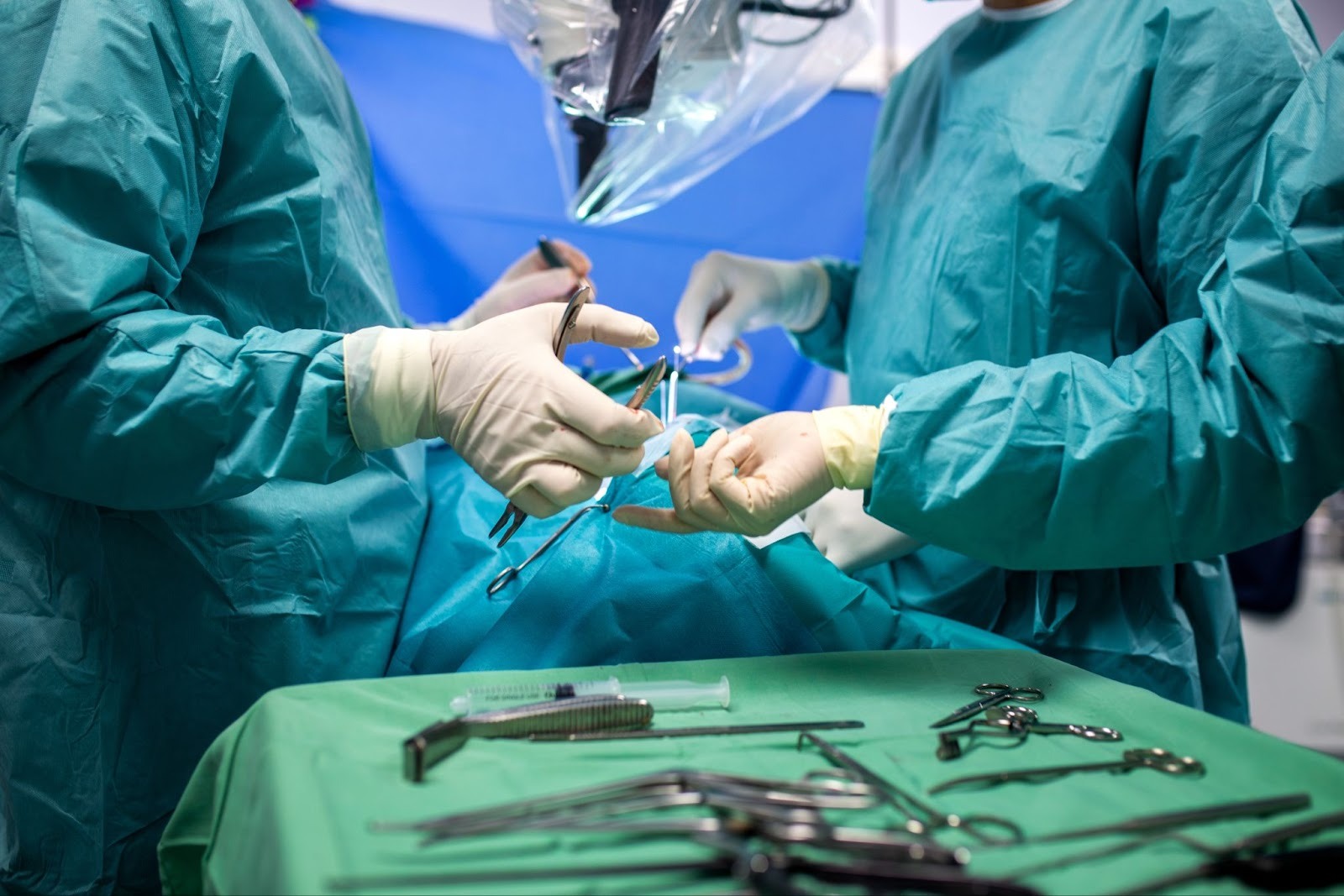 Surgeons picking up surgery tools.