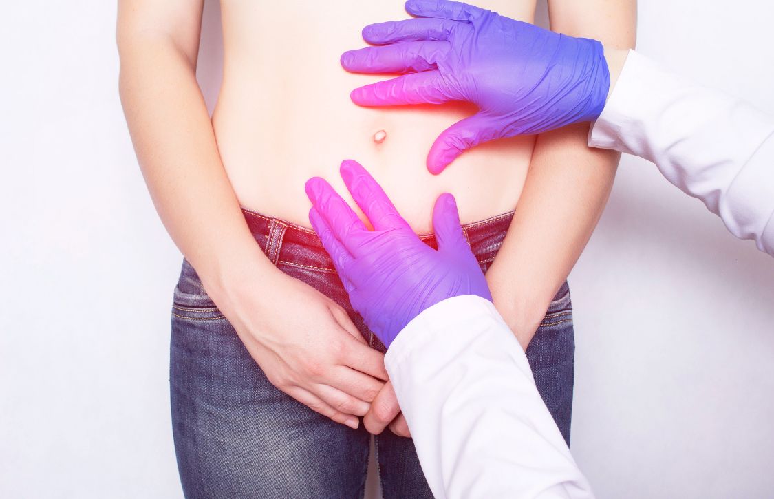 surgeon examining a patient's abdomen to assess abdominal wall closure healing after surgery
