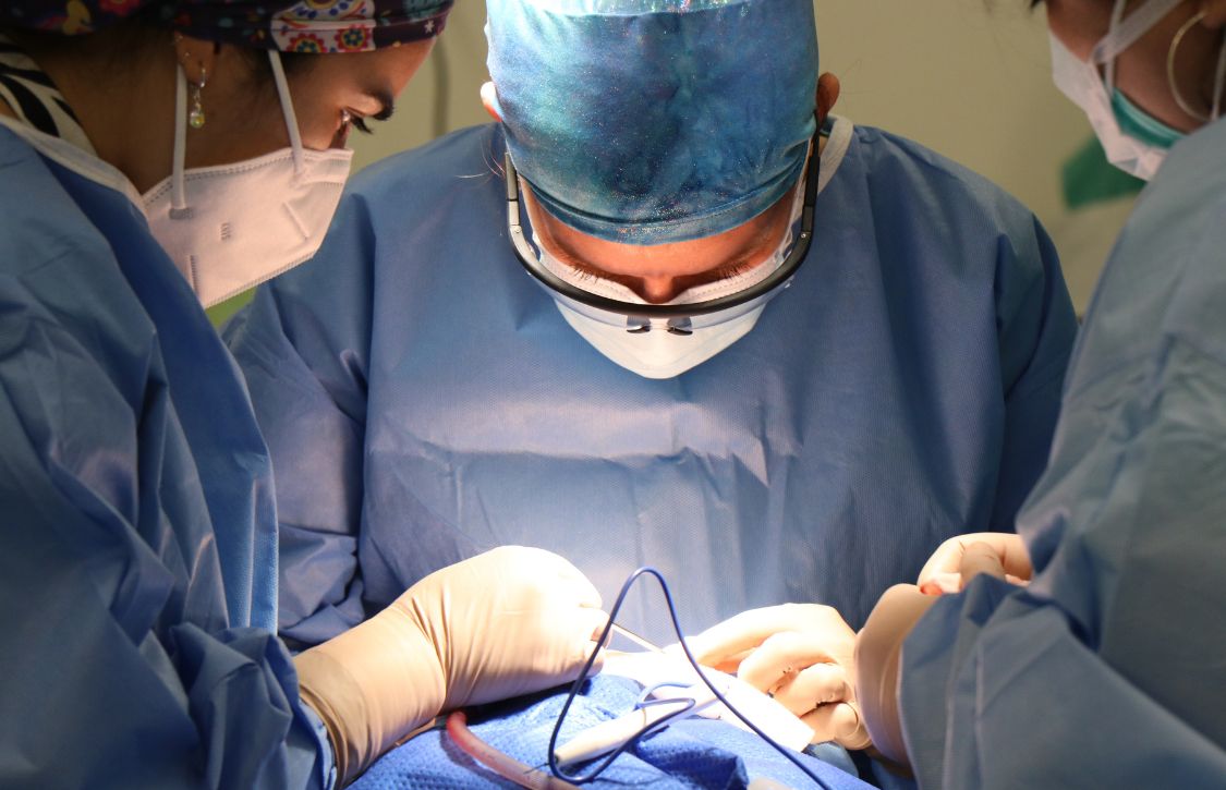 operating room team performing suture passer system closure during surgery