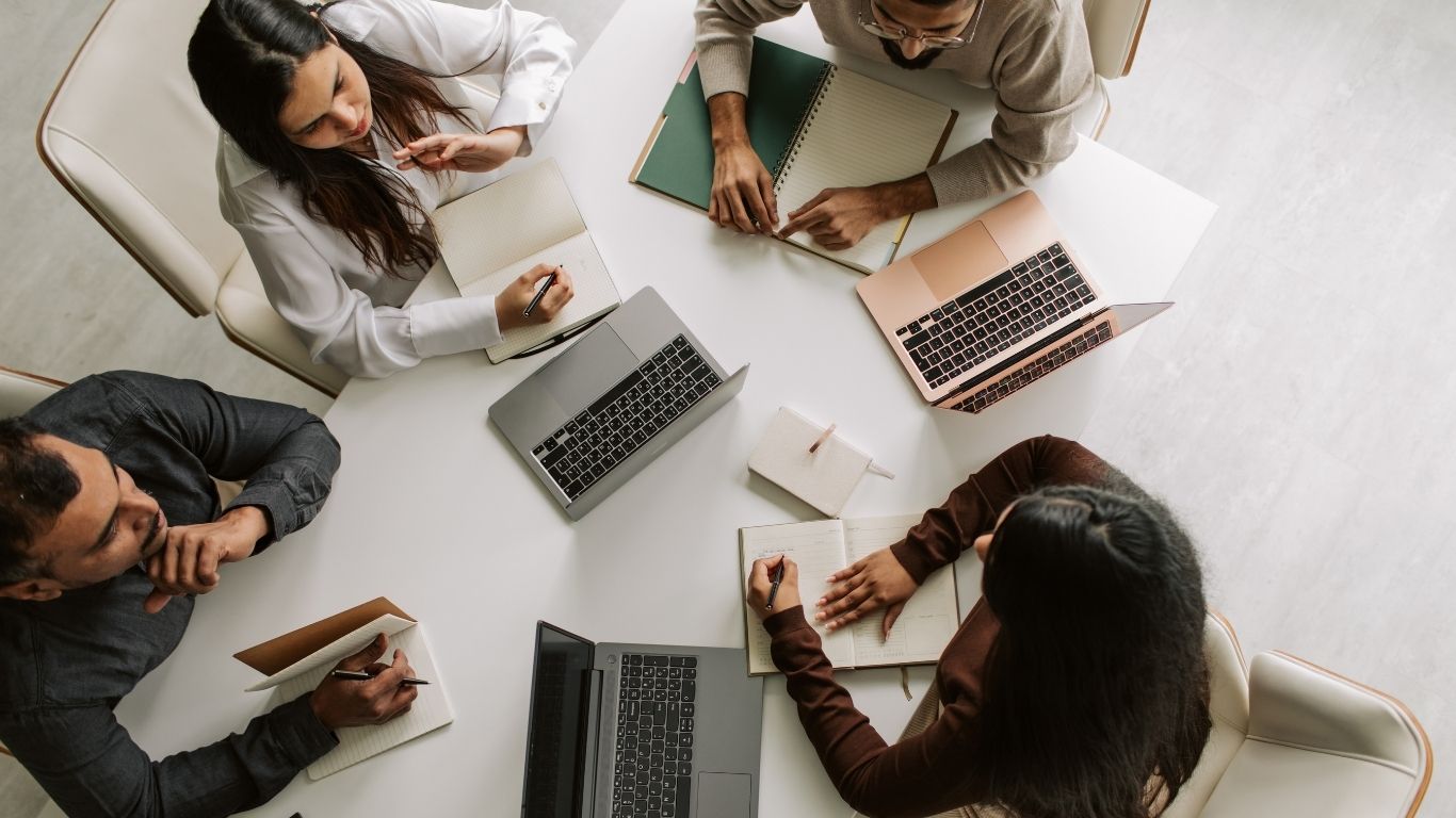 A team of auditors gathered around a table discussing common Post-Closing Defects.