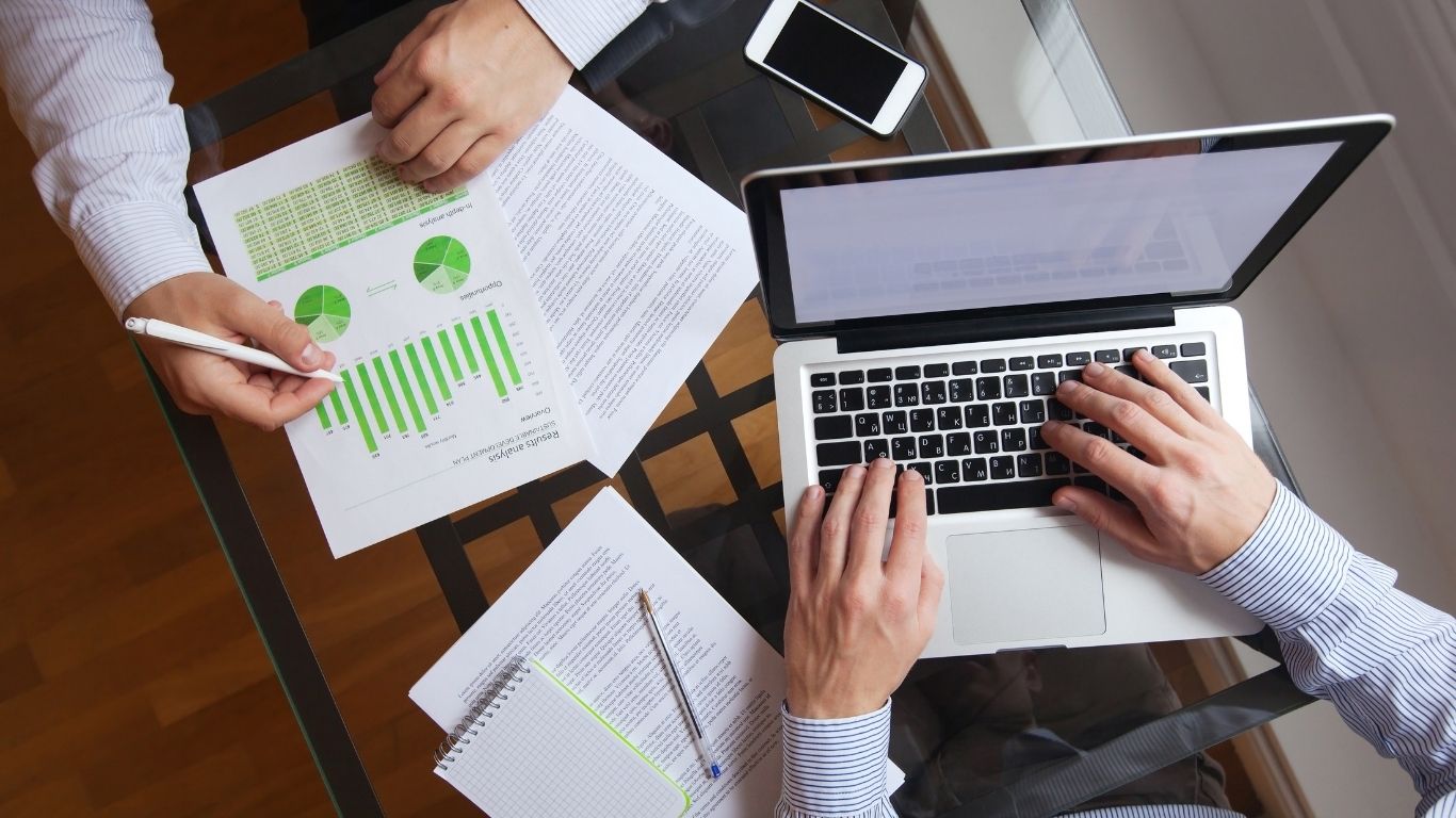 Two evaluators analyzing a report with charts to refine the Underwriting Policy.