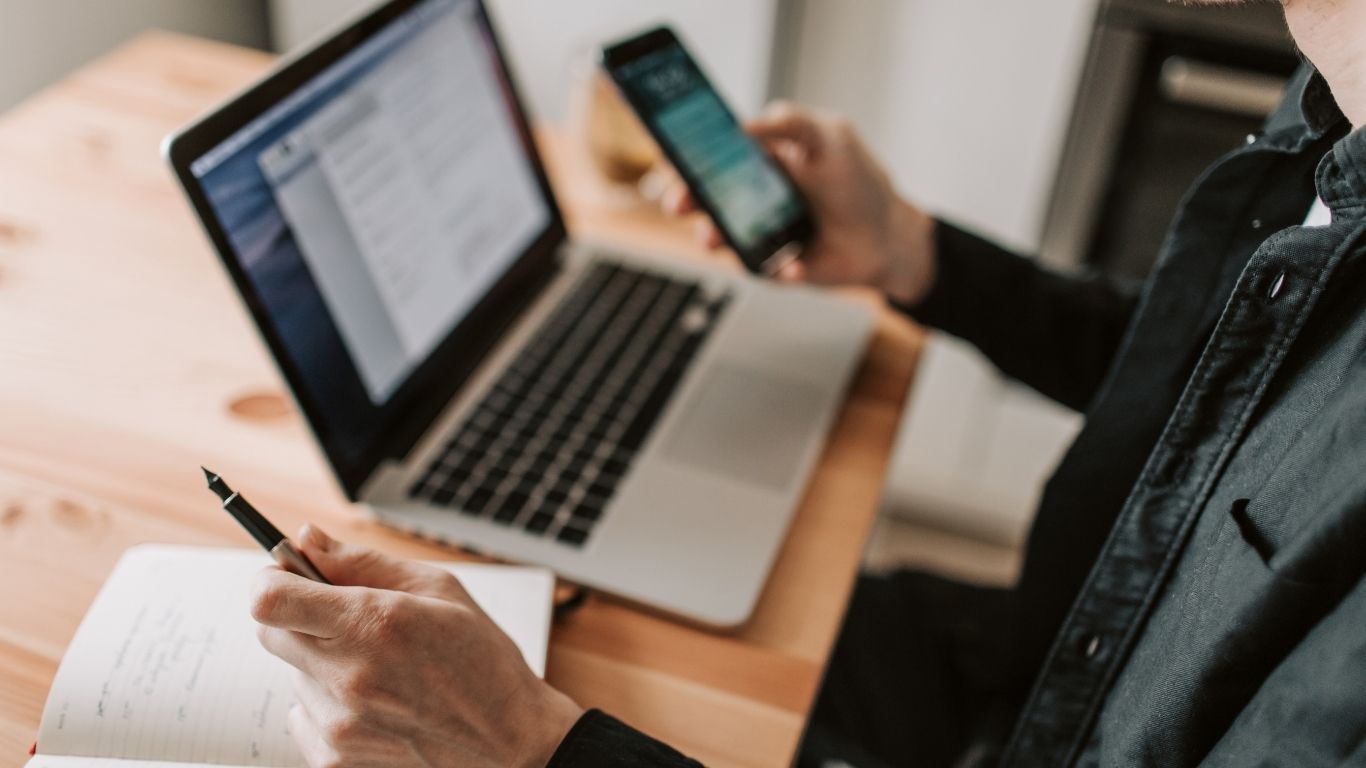 A person using a laptop and phone to manage data for QC Programs.