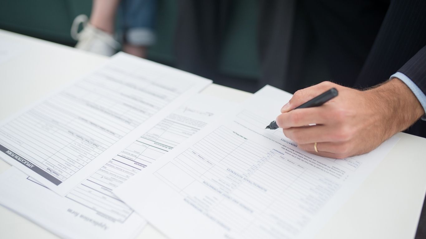 An auditor signing off on paperwork during a Pre-Funding compliance check.