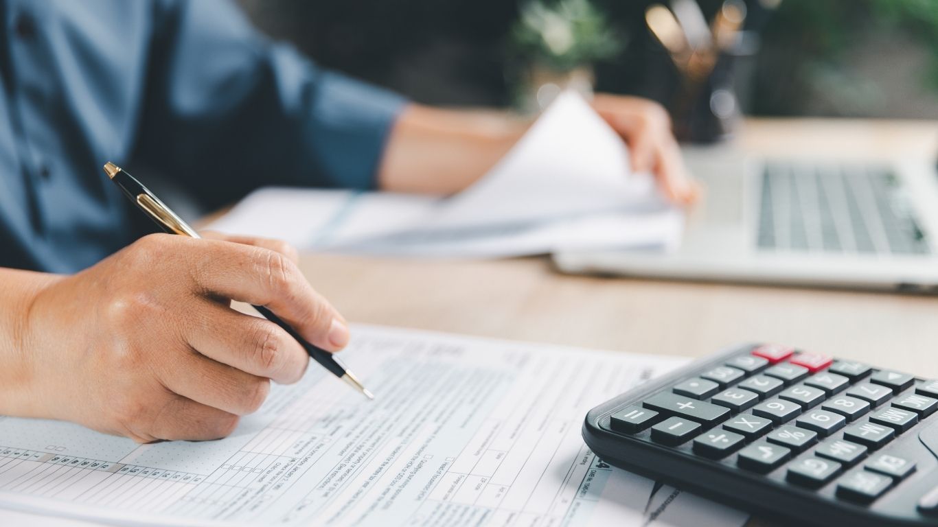 An evaluator checking paperwork at a desk during compliance Reverification.