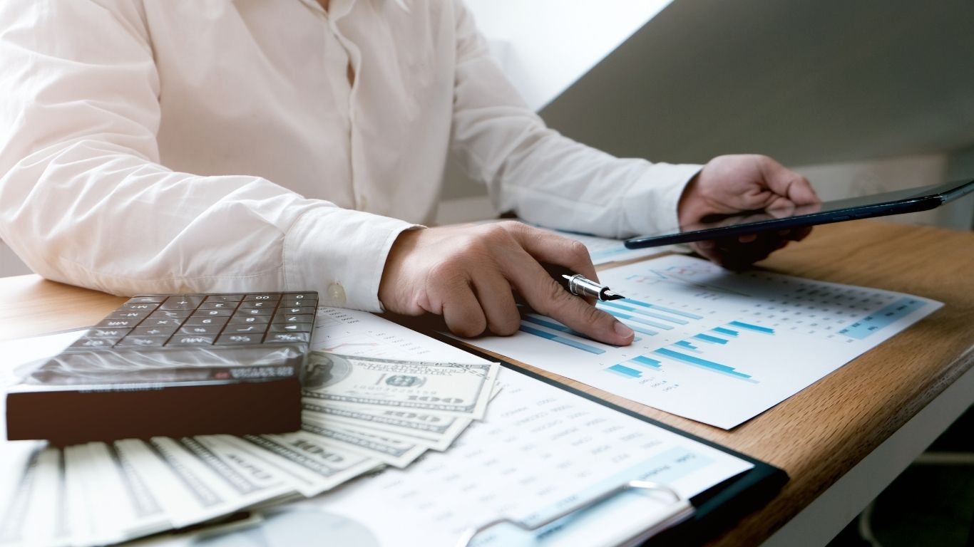 An auditor using a calculator to examine financial documents for a Post-Closing